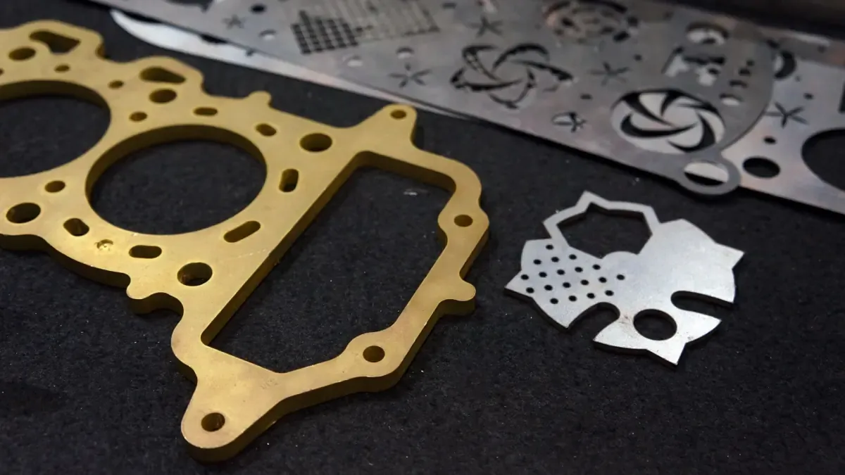 Laser-cut brass and steel sheet metal parts with intricate hole and shape patterns