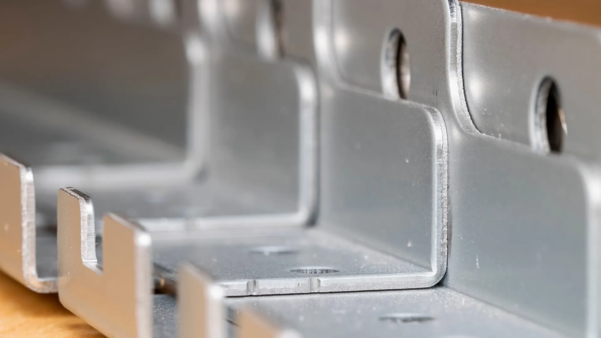 Row of laser-cut stainless steel L-brackets with mounting holes