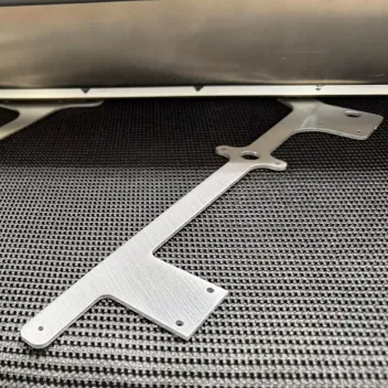 Deburred aluminum L-bracket on a deburring machine conveyor belt
