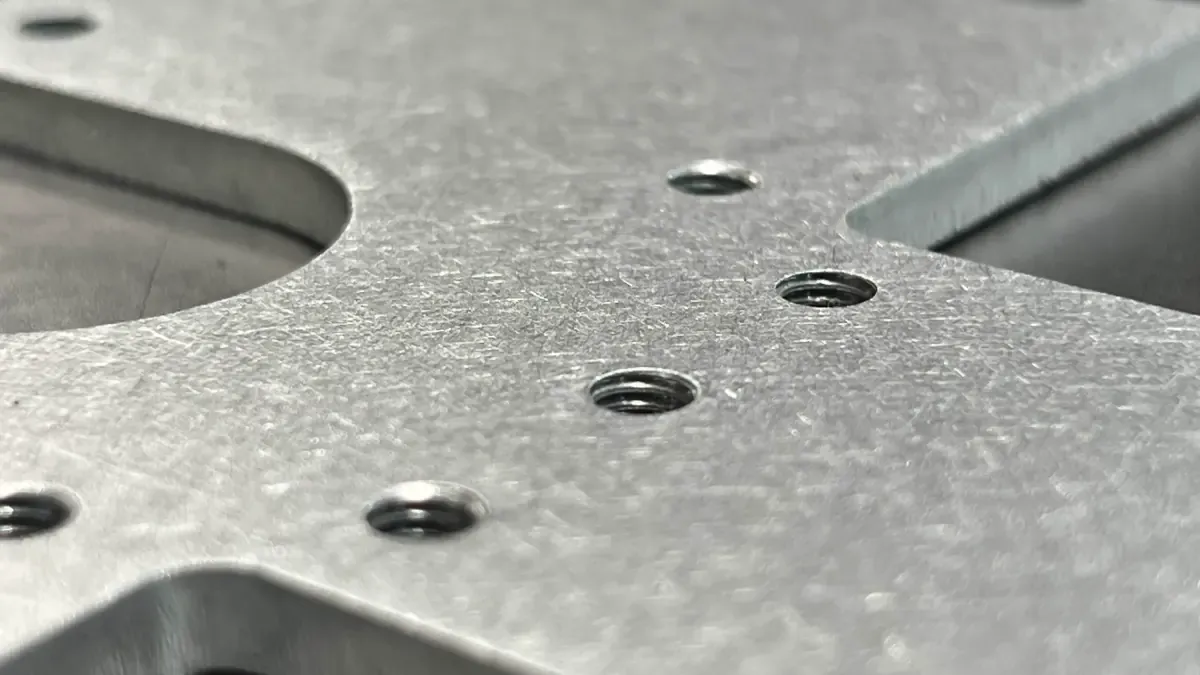 Macro shot of tapped threaded holes in a laser-cut steel plate