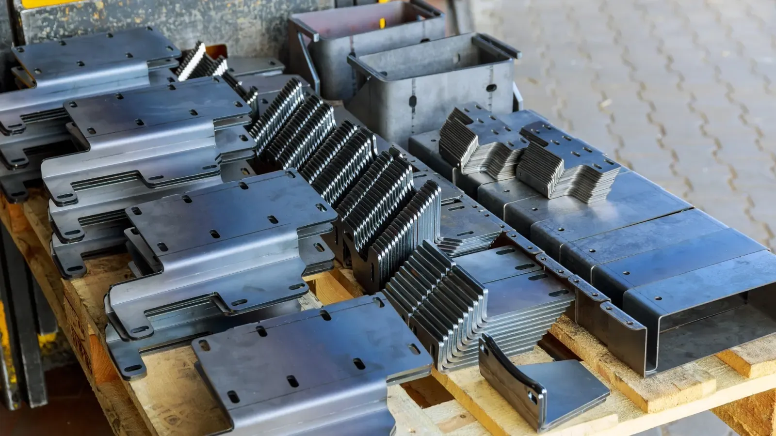 Pallet of stacked laser-cut steel enclosure parts ready for shipping