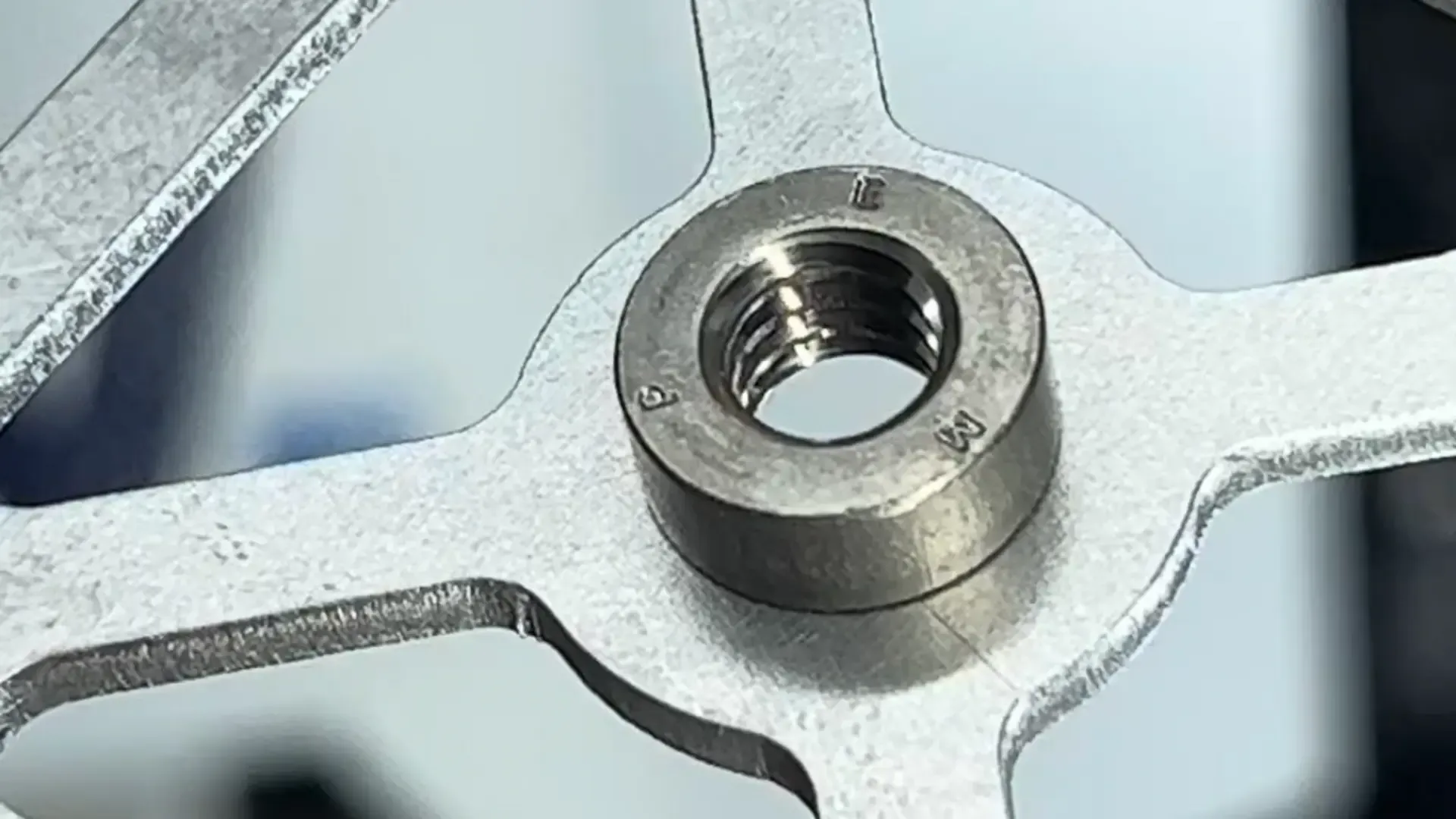 Macro view of a PEM threaded insert pressed into a laser-cut mounting plate