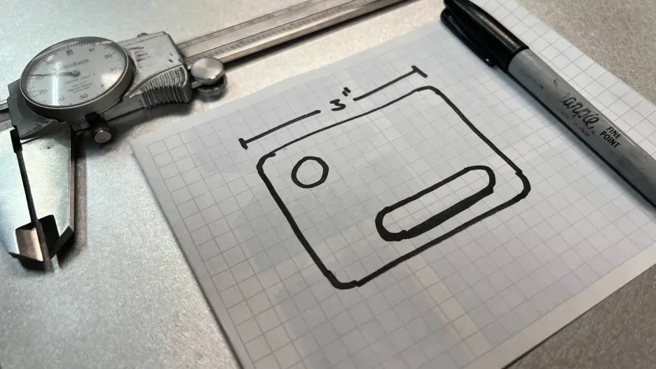 Hand-drawn part sketch on graph paper with a 3-inch dimension, next to a caliper