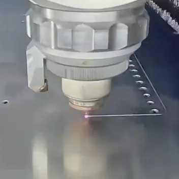 Fiber laser cutting head piercing a steel sheet next to a row of punched holes