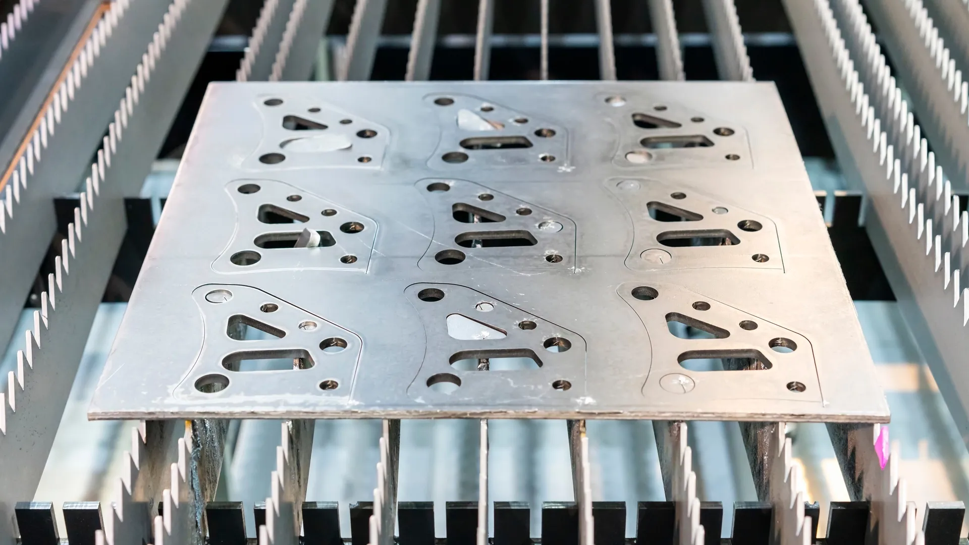 Overhead view of laser-cut bracket parts nested on a sheet metal skeleton