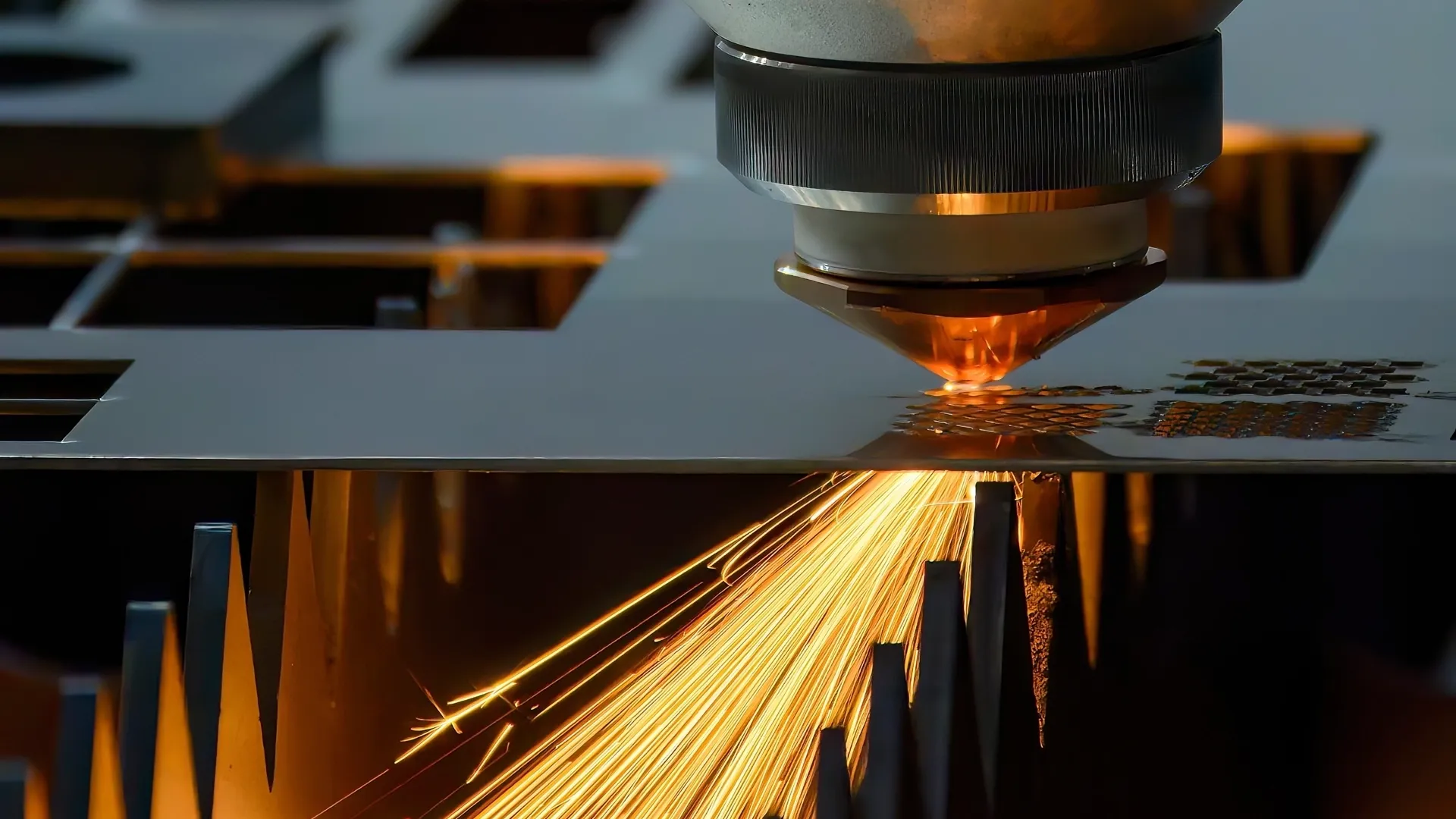 Laser cutting head cutting a nested sheet of bracket parts with sparks flying