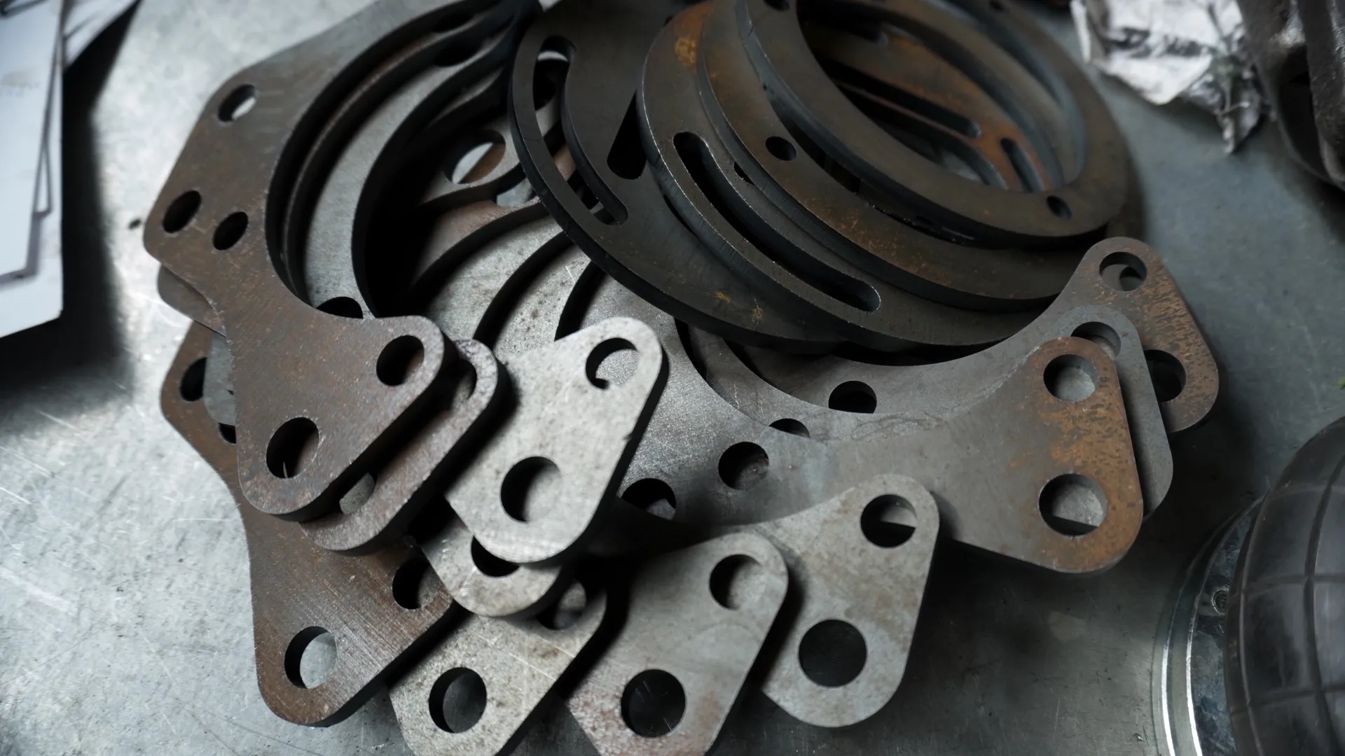 Pile of rusted laser-cut steel bracket parts