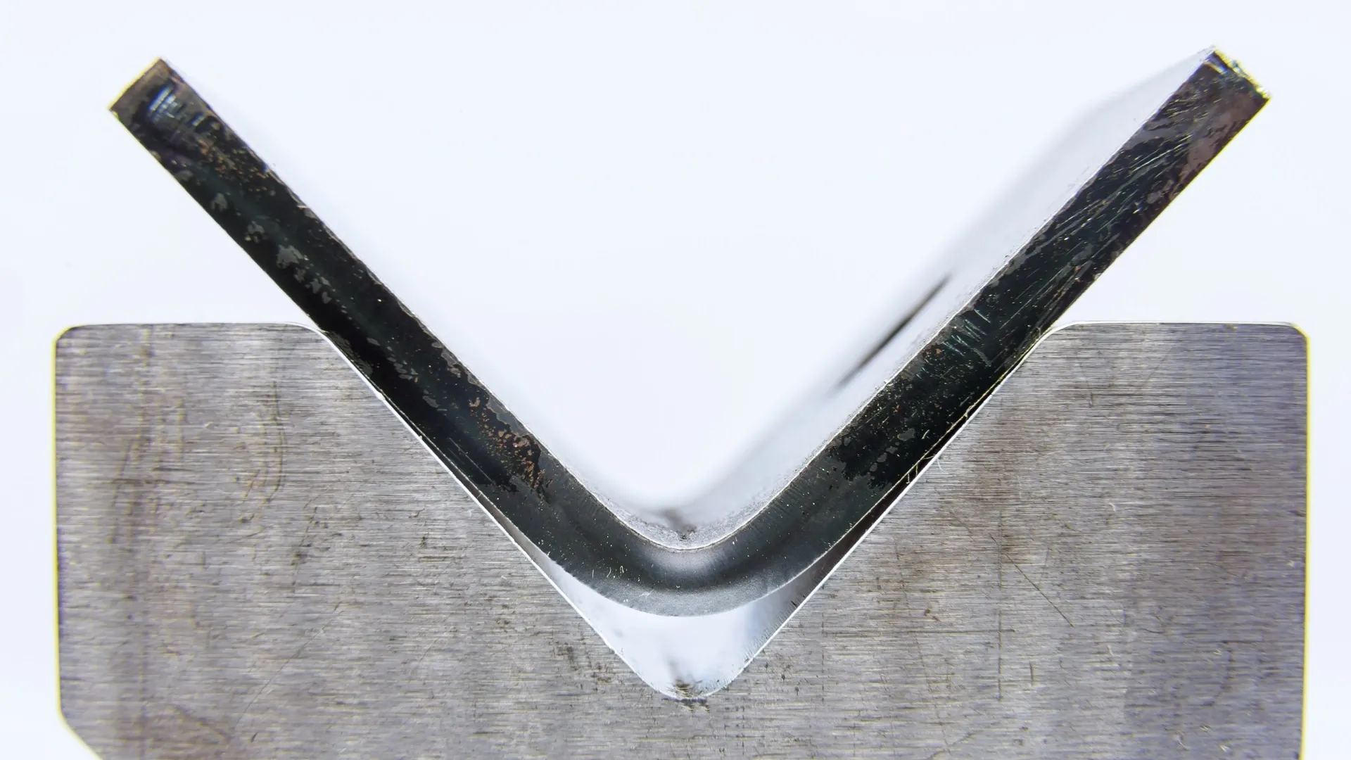 Close-up of a bent sheet metal corner showing the bend radius on a press brake die